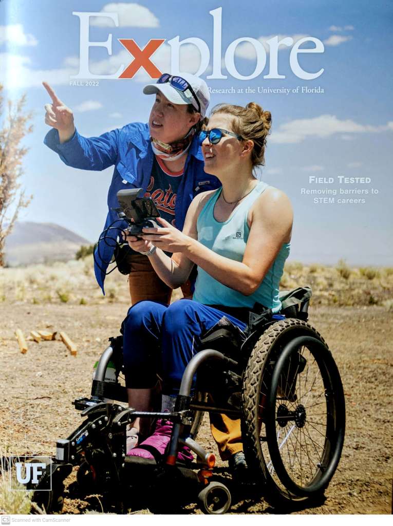 Magazine cover for UF Explore shows Anita pointing up at a drone as a student seated in a wheelchair uses a controller to fly the drone.